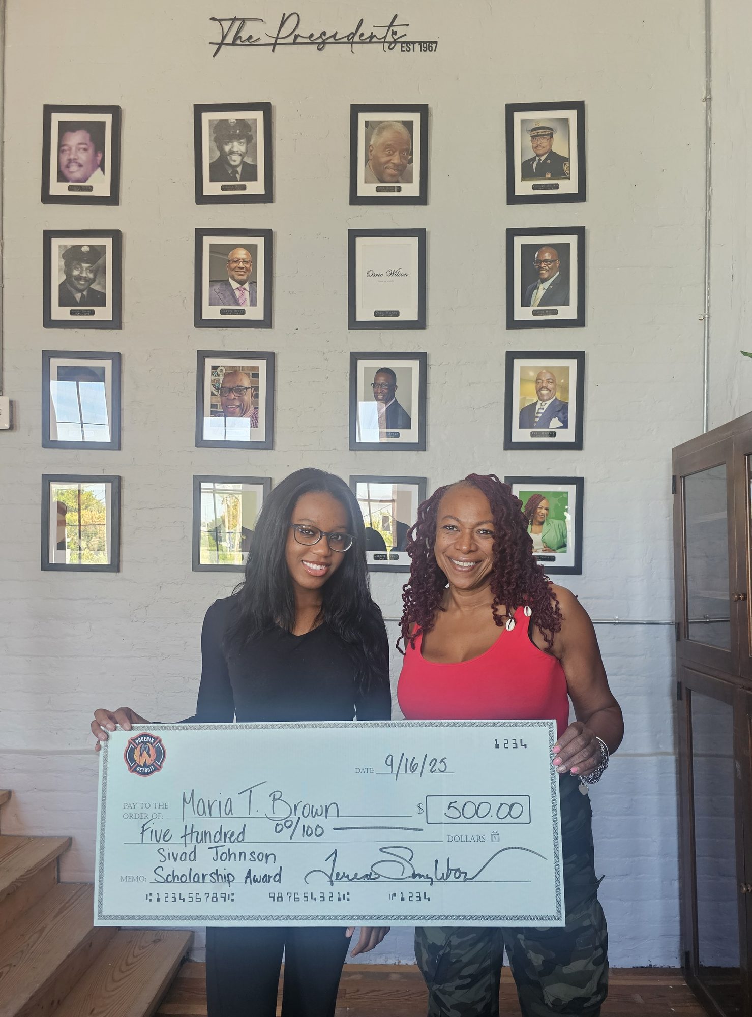 Phoenix scholarship check presentation in front of the Presidents wall at Historic Engine 11.